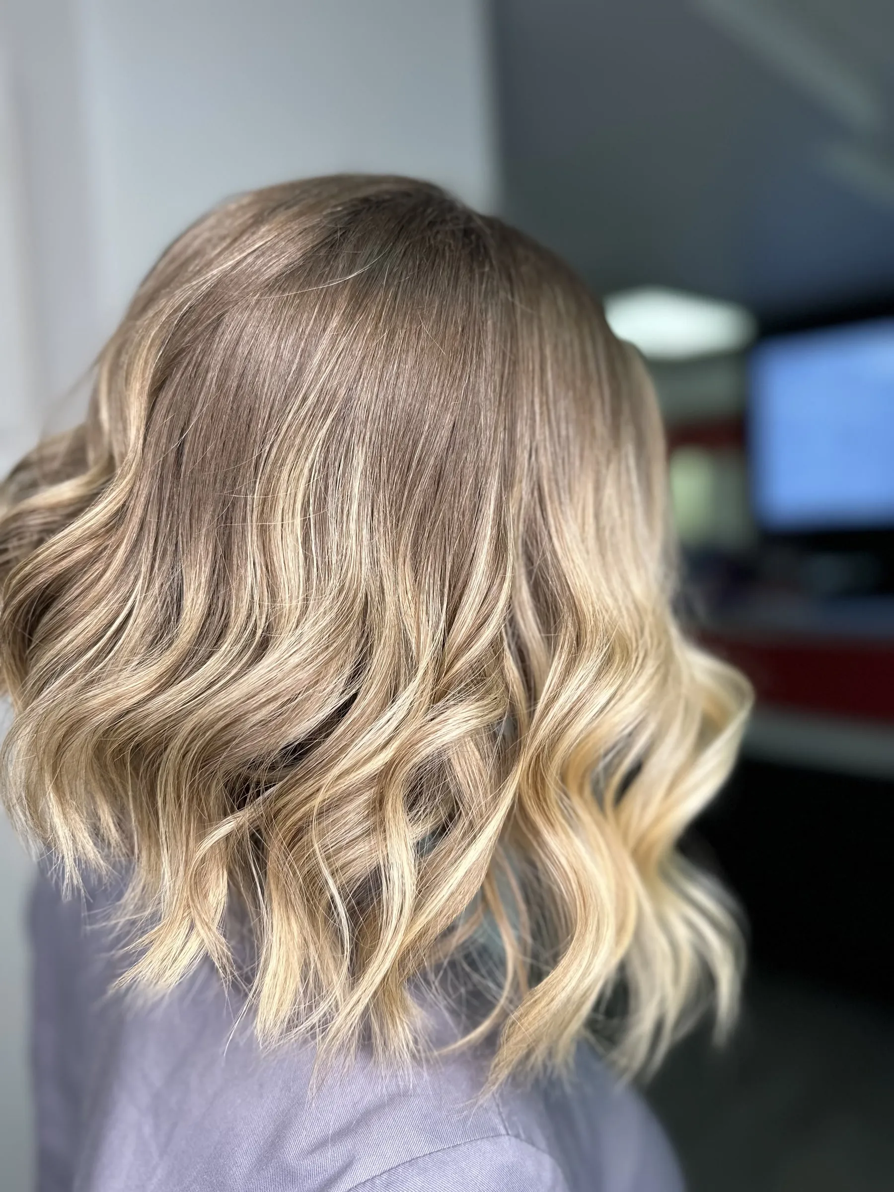 Soft beige blonde balayage on a wavy lob by Ronak Hairstylist in Toronto